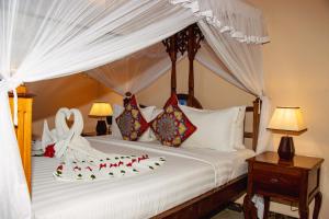 a bedroom with a canopy bed with red flowers on it at Sunny Palms Beach Bungalows in Uroa