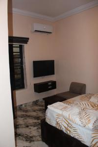 a bedroom with a bed and a flat screen tv at Folks Apartment in Mama