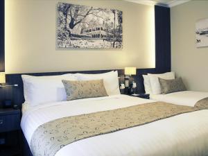 a hotel room with two beds and a painting on the wall at Mercure Orange in Orange +80 photos