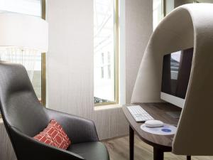 a room with a chair and a computer on a desk at Novotel Charleroi Centre in Charleroi