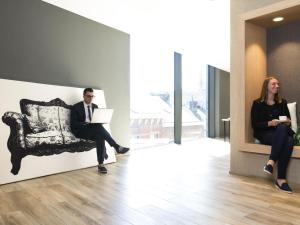 un hombre y una mujer sentados en una silla con un portátil en Novotel Charleroi Centre, en Charleroi