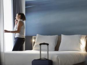 a woman standing next to a bed talking on a cell phone at Novotel Charleroi Centre in Charleroi +73 photos