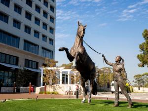 una estatua de un hombre tirando de un caballo con una correa en The William Inglis Mgallery, en Warwick Farm