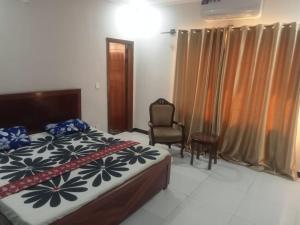 a bedroom with a bed and a chair and curtains at Ryazm Guest house in Rawalpindi