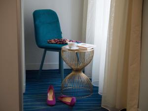 Habitación con silla azul, mesa y zapatos en Hôtel Mercure Paris Suresnes Longchamp, en Suresnes
