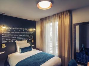 Un dormitorio con una cama y una ventana en Hôtel Mercure Paris Suresnes Longchamp, en Suresnes