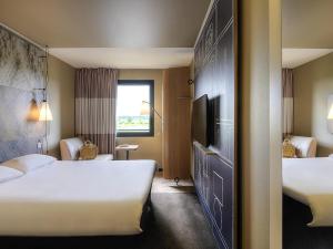 a hotel room with two beds and a tv at ibis Pontorson Baie Du Mont Saint Michel in Saint-Georges-de-Gréhaigne