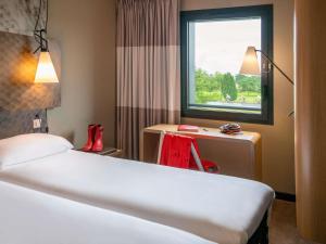 a hotel room with a bed and a window at ibis Pontorson Baie Du Mont Saint Michel in Saint-Georges-de-Gréhaigne