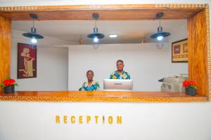 un hombre y una mujer parados detrás de un escritorio con un portátil en Protels La Plage, en Bwejuu