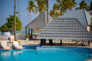 a swimming pool with a gazebo and chairs and palm trees at Protels La Plage Resort in Bwejuu
