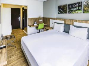 a bedroom with a large white bed and a desk at ibis Styles Confins Aeroporto in Lagoa Santa