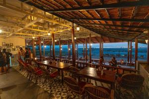 Um restaurante com mesas e cadeiras e vista para o oceano. em The Riverside em Mandrem