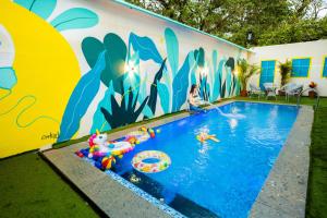 PernemFeel Goa Villa Olive- Unit Of My Booking Guru的一座建筑的一侧,设有一座带壁画的游泳池