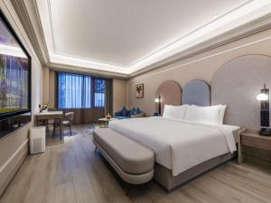 une chambre d'hôtel avec un grand lit et une télévision à écran plat dans l'établissement Mercure Jingjiang Downtown, à Jingjiang