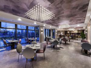 un restaurant avec des tables, des chaises et un lustre dans l'établissement Mercure Jingjiang Downtown, à Jingjiang