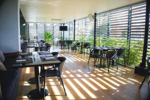 Un restaurante con mesas y sillas en una habitación con ventanas. en Wyndham Concepcion Pettra, en Concepción