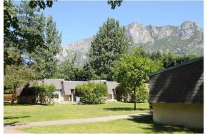 un groupe de bâtiments avec des montagnes en arrière-plan dans l'établissement Chalets et Gites du Quié, aux Cabannes