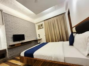 um quarto com uma cama e uma televisão numa parede de tijolos em Stays - Golf Course Road em Gurgaon