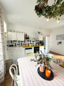 T3 Le Prima - Climatisation - Parking gratuit في بانيير-دوبيغور: مطبخ مع طاولة عليها زهور +5 صور