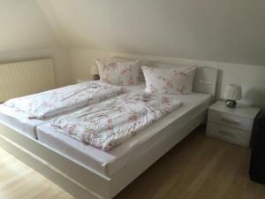 ein weißes Bett mit rosa Bettwäsche und Kissen darauf in der Unterkunft Fewo Zur Ilmenau in Melbeck