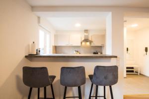une cuisine avec trois chaises devant un comptoir dans l'établissement Luxury Ixheim, à Zweibrücken
