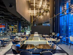 Un comedor con mesas y sillas y grandes ventanales. en TRIBE Budapest Stadium, en Budapest