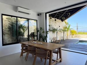 ein Esszimmer mit einem Holztisch und einem großen Fenster in der Unterkunft Villa Vega 3BR Sea View Near Beach in Ungasan
