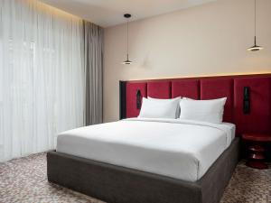 a bedroom with a large bed with a red headboard at Mercure Chisinau Center Jazz Hotel in Chişinău +8 photos