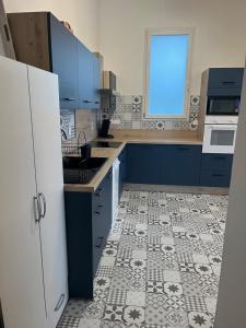une cuisine avec des armoires bleues et un sol carrelé dans l'établissement Gîte de Monplaisir, Pomarez, à Pomarez