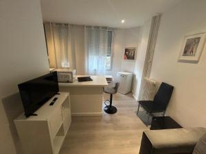 Una pequeña sala de estar con un escritorio y un televisor. en Monaco, en Beausoleil