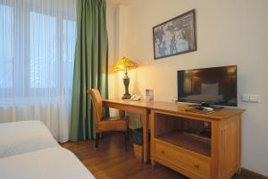 a bedroom with a desk with a television and a bed at Rembrandt Old Town in Bucharest