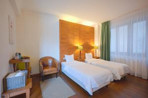 a hotel room with two beds and a chair at Rembrandt Old Town in Bucharest
