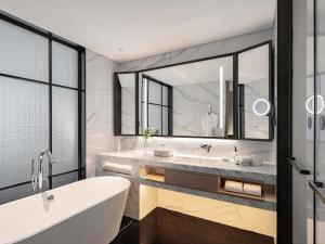 um banheiro com banheira e um espelho grande em Grand Mercure Shenzhen Guangming em Shenzhen