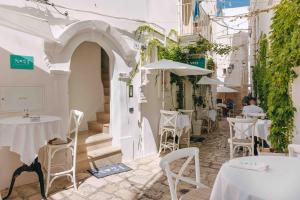a street with white tables and chairs and an alley at Santa Maria 24 in Monopoli