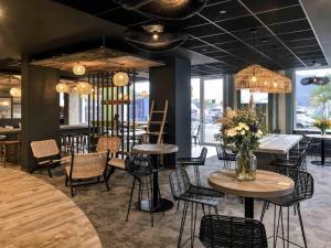 a restaurant with tables and chairs and chandeliers at ibis Styles Bredene in Bredene