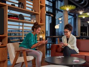 two women sitting in a room looking at their cell phones at Aparthotel Adagio Heidelberg in Heidelberg