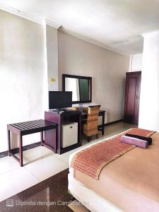 a bedroom with a bed and a desk and a television at kalaki beach hotel in Daru