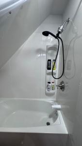 a white bathroom with a light on the wall at Loft Private Studio -- Washer and Dryer -- Near Boston Transit in Malden
