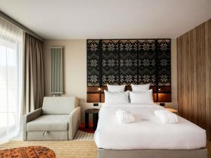Un dormitorio con una gran cama blanca y una silla. en Mercure Szczyrk Resort, en Szczyrk 139 fotos más