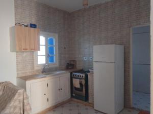Il comprend une cuisine équipée d'un réfrigérateur blanc et d'une cuisinière. dans l'établissement Taguermess 1, à Djerba