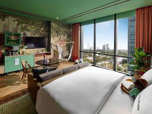 a hotel room with a large bed and a large window at 25hours Hotel Jakarta The Oddbird in Jakarta