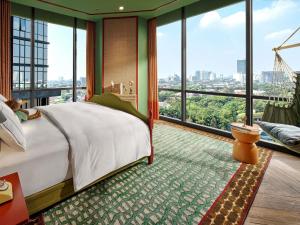 a bedroom with a bed and large windows at 25hours Hotel Jakarta The Oddbird in Jakarta