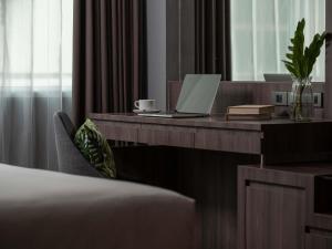 Un dormitorio con un escritorio con una computadora portátil y un espejo. en Novotel Living Bangkok Sukhumvit Legacy, en Bangkok