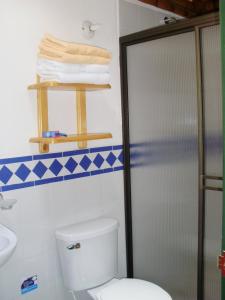 a bathroom with a toilet and a shower and towels at Finca Hotel La Dulcera in Armenia