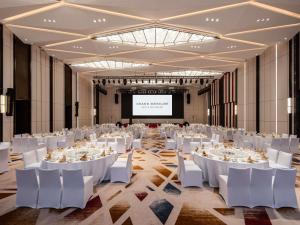 a banquet hall with white tables and chairs and a projection screen at Grand Mercure Yichang Waitan in Yichang +115 photos