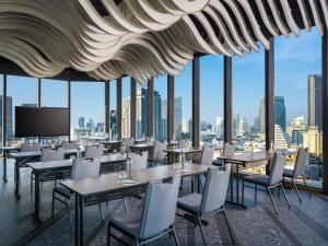 a restaurant with tables and chairs and a view of the city at Mercure Bangkok Surawong in Bangkok