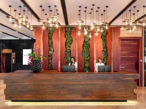 two women sitting at a reception desk in a lobby at Mercure Bangkok Surawong in Bangkok
