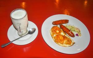 a red table with two plates of food and a glass of milk at Big Spoon Cafe in Eldoret