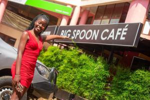 a woman in a red dress standing in front of a sign at Big Spoon Cafe in Eldoret