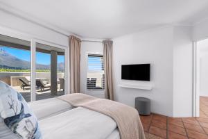 开普敦Pingu Beachhouse with Jacuzzi Hout Bay Cape Town的一间卧室设有一张床、一台电视和一个阳台。